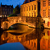 1614 | 1608 Photo: A canal reflects a bridge and traditional buildings in the historic center of Bruges.