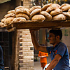 Starch Source Photo: A bicycle bread delivery guy carries a rack of fresh bread on his head.